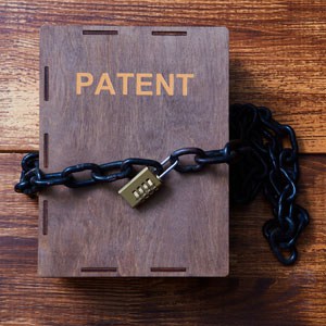 A patent document rests on a wooden table, secured with a chain and padlock - J. H. Lin Patent Law PC